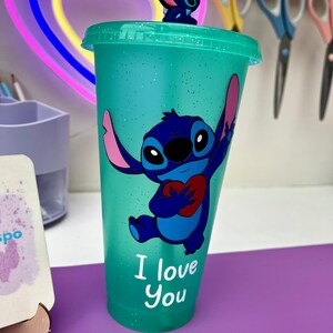 Puede incluir: Un vaso reutilizable azul turquesa con acabado brillante presenta un personaje de dibujos animados azul sosteniendo un coraz&oacute;n rojo. El personaje es Stitch de la pel&iacute;cula de Disney Lilo & Stitch. El texto "I love you" est&aacute; impreso en el vaso.
