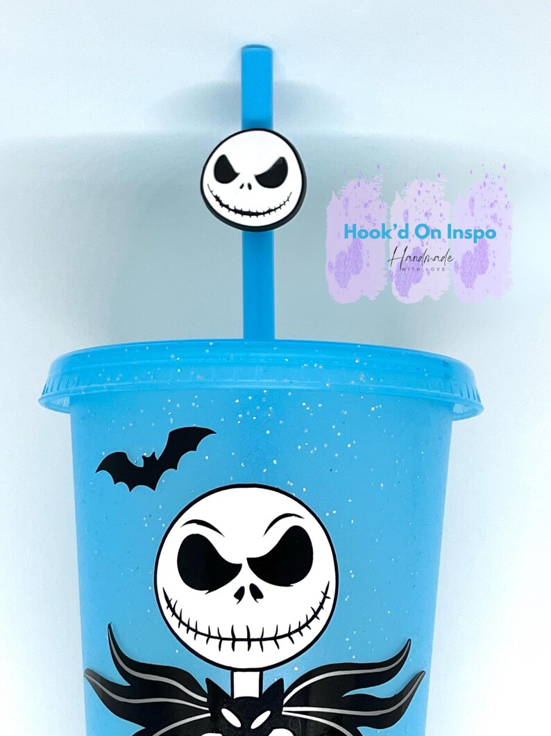 Puede incluir: Un vaso azul claro con una pajita a juego y un dise&ntilde;o de Jack Skellington. El vaso presenta un murci&eacute;lago negro y una gran cara de Jack Skellington. La pajita tiene un dije con la cara de Jack Skellington. El vaso est&aacute; decorado con purpurina.