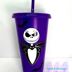 Puede incluir: Un vaso morado con un dise&ntilde;o de Jack Skellington de Pesadilla antes de Navidad. El vaso tiene una tapa y una pajita a juego, rematadas con una cara de Jack Skellington. Tambi&eacute;n hay siluetas de murci&eacute;lagos negros en el vaso.