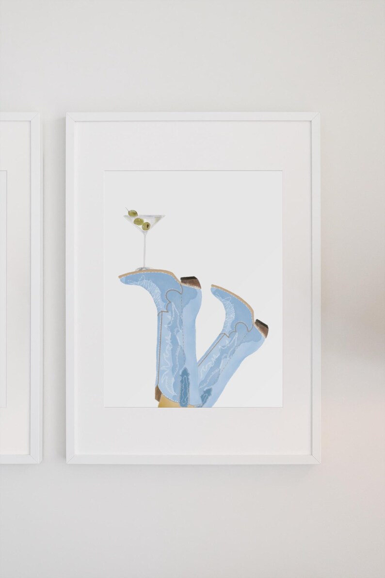 May include: A framed illustration of a pair of light blue cowboy boots with a martini glass resting on top. The martini glass has two green olives in it.