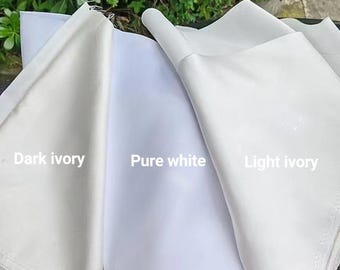 Pode incluir: Três amostras de tecido exibidas lado a lado com texto. A amostra da esquerda está rotulada como Dark ivory, a central como Pure white e a da direita como Light ivory. O tecido parece liso e opaco.