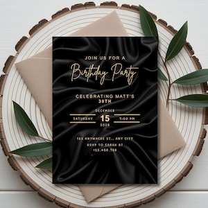May include: A black birthday party invitation with gold text, featuring the words "Join us for a Birthday Party" and event details. The invitation is set on a wooden slice with a beige envelope and green leaves.
