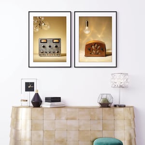 May include: Two framed vintage-style prints. One features a silver audio control panel with knobs and dials. The other showcases a wooden antique radio with a decorative front. Both are set against a warm, neutral background.
