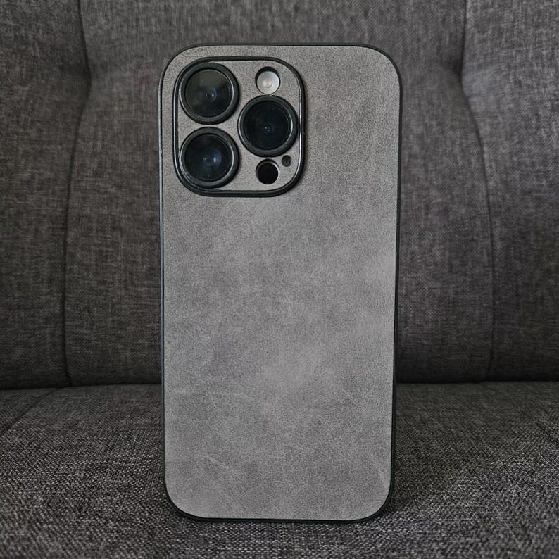 May include: A grey phone case with a textured finish. The case has a black camera bump with three lenses.