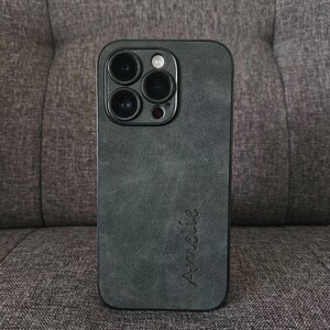 May include: A black phone case with a textured, suede-like finish. The case has a raised camera bump with four lenses and the word "Am&eacute;lie" written on the back.