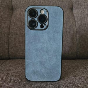 May include: A blue phone case with a textured finish. The case has a raised camera bump with four black camera lenses.