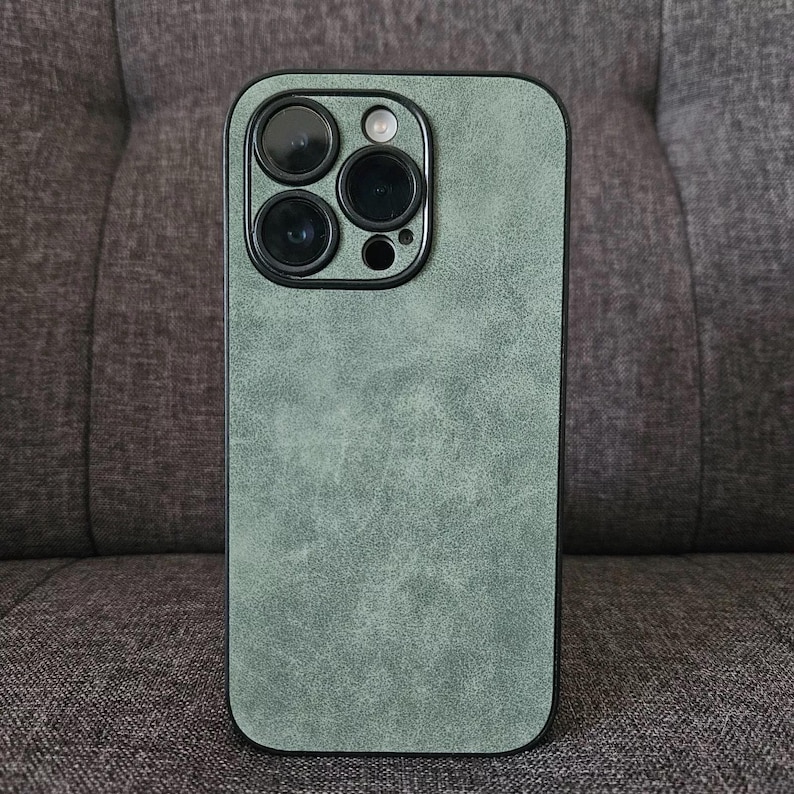May include: A green phone case with a textured surface and a black camera bump with four lenses.