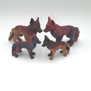 May include: Four red and black articulated fox figurines. The foxes are posed in a circle, facing each other. The figurines are made of plastic and have a realistic appearance.