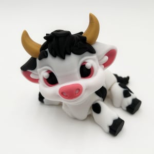 May include: A charming, cartoon-style cow figurine. The cow is primarily white with black spots, black hair, and pink accents on the ears and nose. It has large, expressive eyes and small, yellow horns. The cow is lying down.