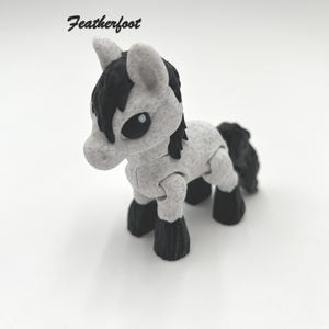 May include: A small, gray and black toy horse with articulated legs. The horse has a black mane and tail.