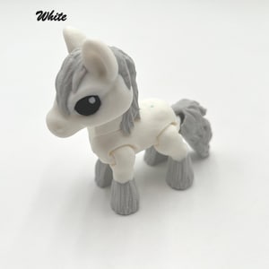 May include: White toy horse with gray mane and tail. The horse has articulated legs and a cute face.