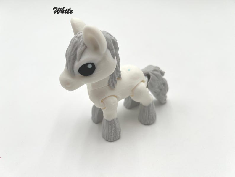 May include: White toy horse with gray mane and tail. The horse has articulated legs and a cute face.