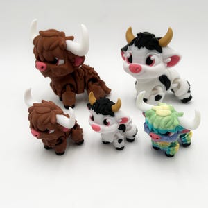 May include: A collection of five miniature Highland cow figurines. The figurines feature detailed designs with varying colors, including brown, white, and a colorful tie-dye pattern. Each cow has horns and a fluffy appearance.