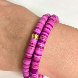 May include: A pink and purple layered bracelet with gold accents. The bracelet is made of small, round beads.