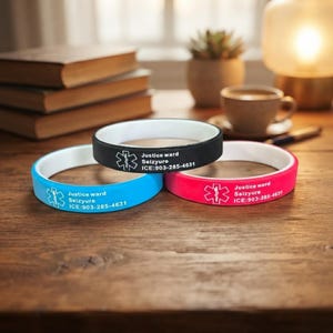 May include: Three silicone medical alert bracelets in black, blue, and pink, each with a white interior. Each band features a white Star of Life symbol, the text Justice ward Seizyure, and the contact information ICE:903-285-4631 printed in white.