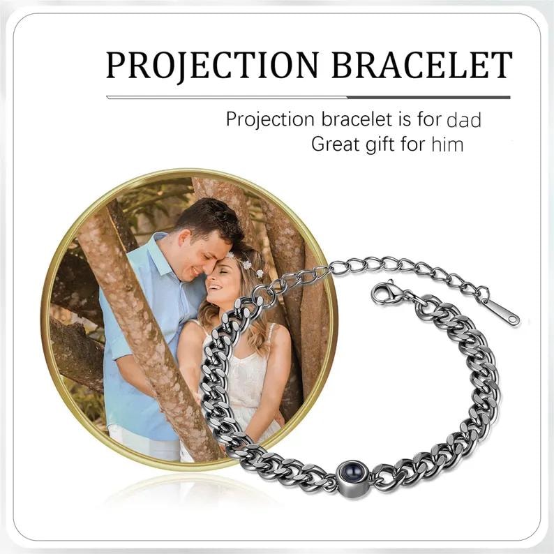 May include: A silver projection bracelet with a chain link design. The bracelet features a small, round projection element. The image also includes a circular photo of a couple. Text on the image reads "Projection Bracelet".