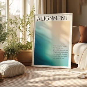May include: A framed print with the word "ALIGNMENT" at the top. The artwork features a gradient of colours, transitioning from blue to yellow. Below the title is a description about energy and feeling grounded.