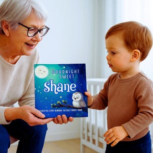 May include: A personalized children's book titled "Goodnight Sweet Shane" with a blue cover featuring a moon, stars, and an owl. The book is being held by a person and shown to a young child. The book's title is in white and the child's name is in a large, stylized font.