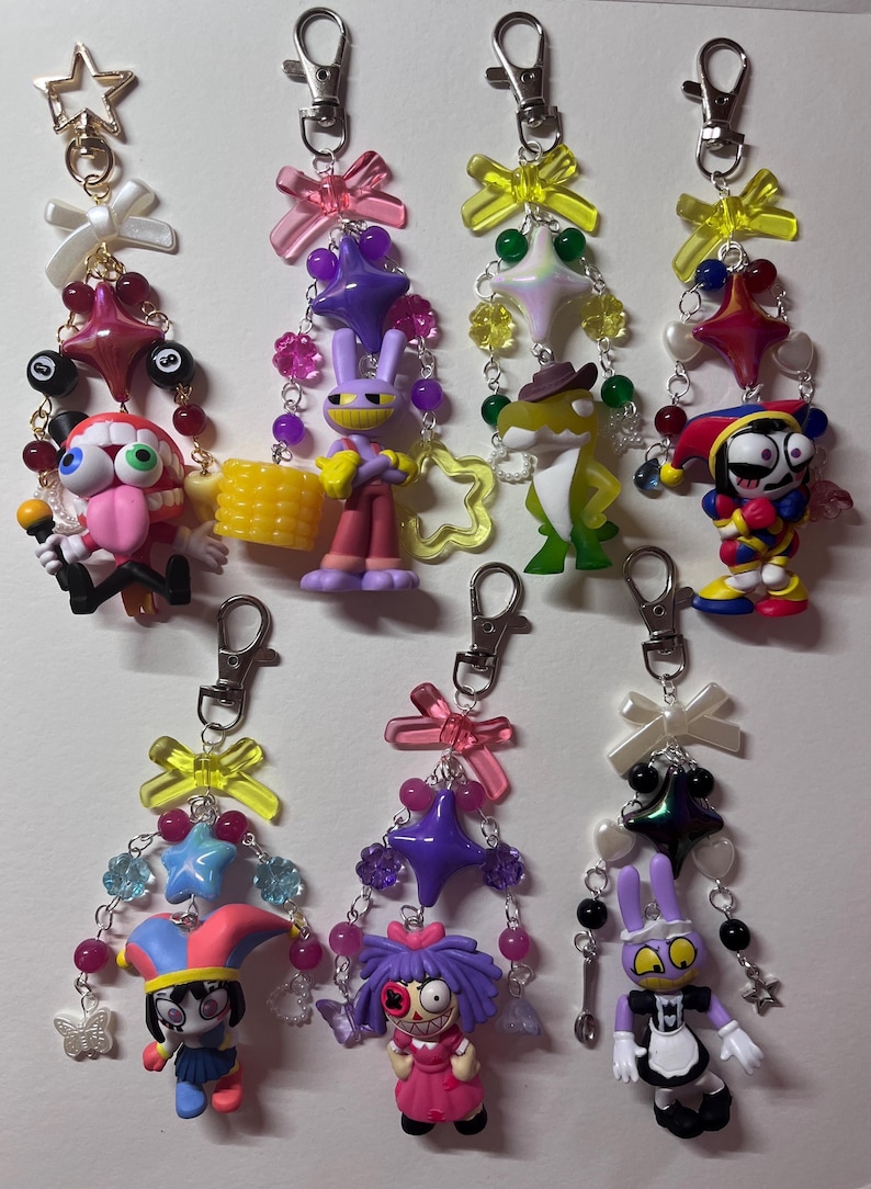 May include: Seven decorative keychains featuring various cartoon character figures, colorful plastic bows, star-shaped charms, and assorted beads attached to silver-toned metal lobster clasps. Each keychain displays a unique combination of character.