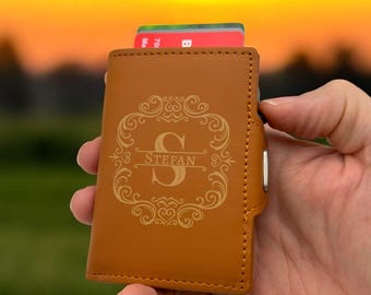May include: A brown leather wallet with a gold engraved monogram and the name "STEFAN".