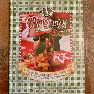 Op de afbeelding: Een groene en witte geruite boekomslag met een ganzen- en bessenlogo. De titel is "Christmas" met de ondertitel "Book 9". De tekst luidt: "Onze lekkerste kerstrecepten, cadeaus om te maken en te geven, en frisse ideeën die het seizoen laten stralen!"