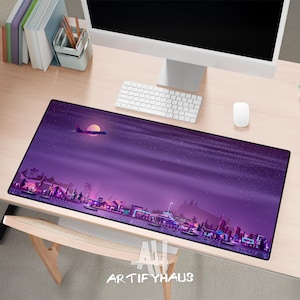 May include: A rectangular desk mat with a purple night sky design. The mat features a cityscape silhouette with buildings, trees, and a plane flying near the moon. The text "ARTIFYHAUS" is at the bottom.