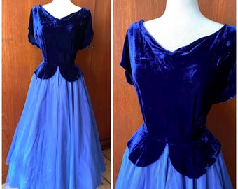 May include: A vintage blue velvet dress with a V-neckline and short sleeves. The bodice is a deep blue velvet, and the skirt is a lighter blue, flowing fabric. The dress is displayed on a mannequin.