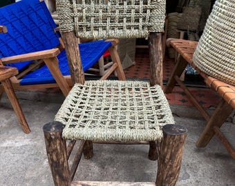 May include: A wooden chair with a woven seat and back. The chair is made of natural wood and has a rustic look. The chair is sitting on a concrete floor.