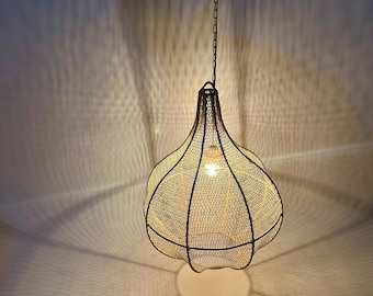 May include: A hanging light fixture with a bulb inside, encased in a wire mesh shade. The shade is a bulbous shape with a dark metal frame. The light casts a pattern on the wall and ceiling.