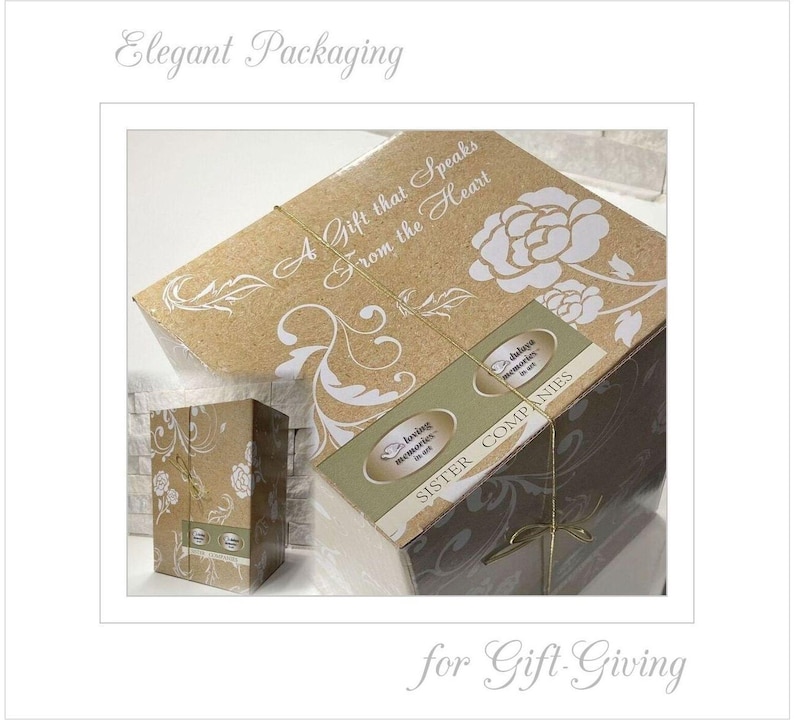 May include: A brown cardboard box with a floral design and the text "A Gift that Speaks From the Heart". The box is tied with a gold ribbon and has two labels that say "Loving Memories" and "Sister Companies".
