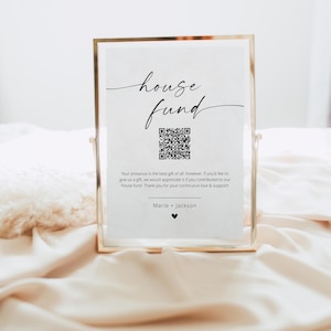 Pode incluir: Uma placa emoldurada em dourado com as palavras "house fund" em escrita cursiva. Abaixo do texto há um código QR. A placa está em uma moldura dourada e repousa sobre uma superfície acetinada. O texto abaixo do código QR diz "Sua presença é o melhor presente."