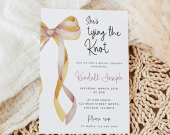 May include: Bridal shower invitation with watercolor bow and ribbon design in shades of gold and mauve. The text reads "She's tying the Knot" and includes details for the event, such as the date, time, location, and RSVP information.