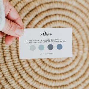 May include: A white card with the word "attire" in cursive script, held against a woven background. The card includes text encouraging guests to wear specific colors, with a "black tie optional" note and a color palette of blues.