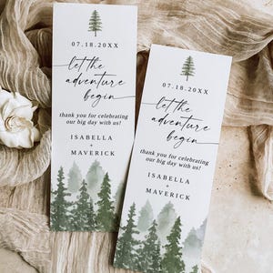 Könnte beinhalten: Zwei weiße Hochzeitseinladungskarten mit einem Waldmotiv. Die Karten tragen den Text "let the adventure begin" und die Namen Isabella und Maverick. Die Karten enthalten auch das Datum 07.18.20XX und den Satz "thank you for celebrating our big day with us!"