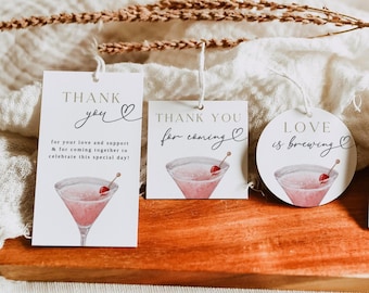 Può includere: Tre etichette regalo bianche con spago, con un'illustrazione ad acquerello di un cocktail rosa con una ciliegia. Le etichette recitano "Grazie" e "L'amore si sta preparando". Un'etichetta include il testo "per il tuo amore e supporto e per celebrare questa giornata speciale!"