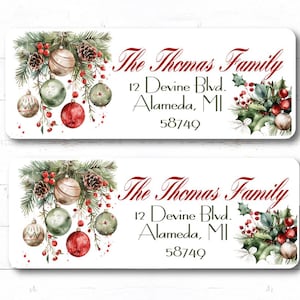 May include: Two rectangular address labels featuring a watercolor illustration of pine branches, pinecones, red berries, and Christmas ornaments. The text reads The Thomas Family, 12 Devine Blvd., Alameda, MI 58749 in a decorative script and serif font.