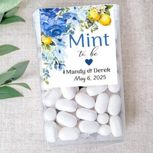 May include: Clear plastic box filled with white mints. The box has a label with blue floral designs, lemons, and the text "Mint to be" with a heart, names, and a date.