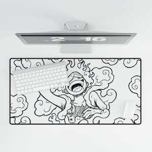 Op de afbeelding: Een zwart-witte bureaumat met een cartoonillustratie van een personage met een open mond en rookachtige ontwerpen. Een wit toetsenbord en muis liggen op de mat. De mat is rechthoekig.