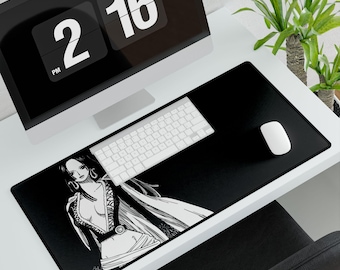 Puede incluir: Alfombrilla de escritorio negra con una ilustración en blanco y negro de un personaje de anime femenino. Un teclado y un ratón blancos están sobre la alfombrilla. Un monitor de ordenador muestra la hora 14:16. Una planta verde está en el fondo.