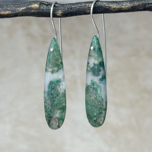 May include: A pair of silver dangle earrings with green and white agate teardrop shaped stones.