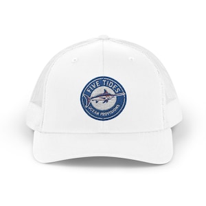 May include: White trucker cap with a mesh back and a curved peak. The front displays a circular patch with a blue and white marlin design and the text "FIVE TIDES OCEAN PROVISIONS" in a circular pattern.