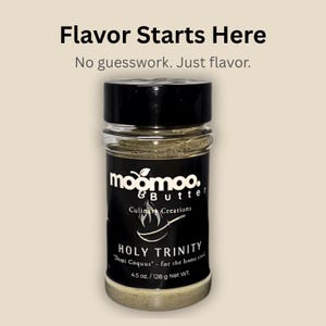Puede incluir: Un frasco de especias transparente con tapa negra, etiquetado "moomoo & Butter Culinary Creations". La etiqueta dice "HOLY TRINITY" y "Demi Coquus" con un peso neto de 128 g. El texto "Flavor Starts Here" y "No guesswork. Just flavor" están en la parte superior.