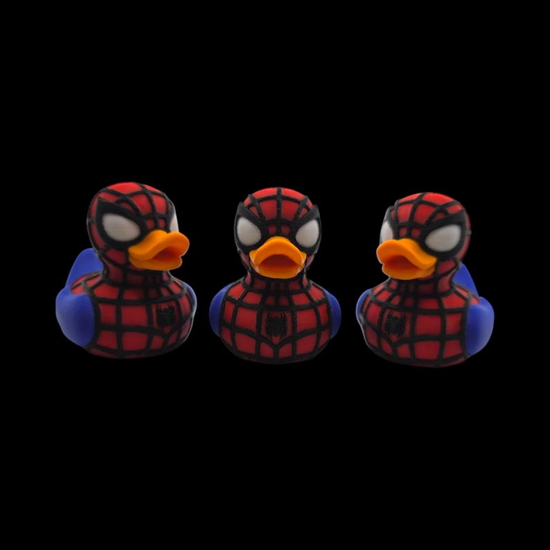以下が含まれることがあります： スパイダーマンの格好をした3匹のアヒルのラバーダック。各アヒルは赤と黒のウェブ模様、白い目、オレンジ色のくちばしを持っています。アヒルは青い翼と胸にスパイダーマンのロゴが付いています。