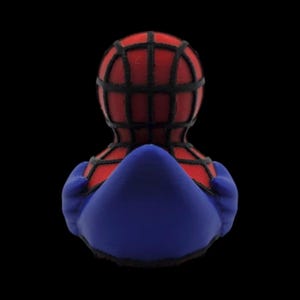 以下が含まれることがあります： スパイダーマンをテーマにしたラバーダック。赤い頭に黒いクモの巣模様、青いボディが特徴です。全体的なデザインは、スーパーヒーローを様式化したものです。