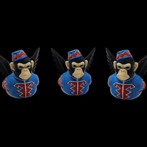 May include: Three monkey busts with black wings, wearing blue and red outfits and hats. The monkey faces are light-colored, with dark fur around the eyes and ears. The background is solid black.