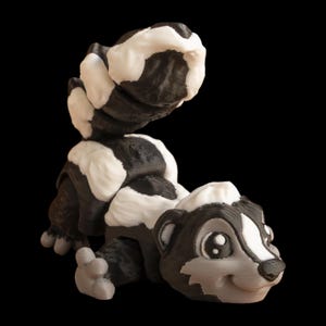 May include: A 3D-printed skunk model in black and white, depicted in a relaxed pose. The skunk has a fluffy tail and a smiling expression. The design shows detailed textures. The figurine is set against a black background.