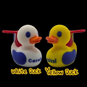 May include: Two rubber duck toys, one white and one yellow, with blue and orange accents. The white duck has the word "Carni" printed on it, and the yellow duck has the word "nival" printed on it. The text "White Duck Yellow Duck" is below the ducks.