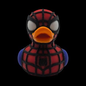 以下が含まれることがあります： スパイダーマン風のラバーダック。赤と黒のウェブスーツ、黒いマスク、白い目。オレンジ色のくちばしと青い肩のアクセントがあり、胸にはクモのエンブレムが付いています。