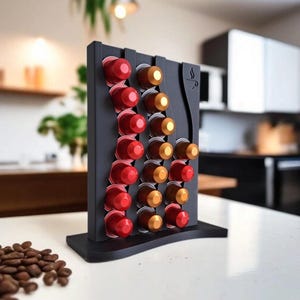 Könnte beinhalten: Ein schwarzer Kaffeepad-Halter mit geschwungenem Design, der rote und goldene Kaffeepads hält. Der Halter steht auf einer weißen Oberfläche, mit Kaffeebohnen im Vordergrund. Der Halter hat eine Kaffeetassen-Grafik.