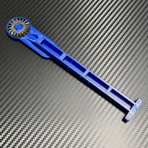 May include: A blue plastic tool with a gear-like head and a T-shaped handle. The tool is designed for tightening or loosening screws.